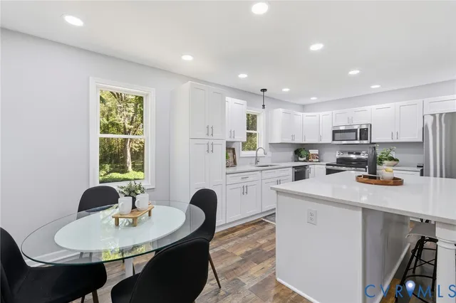 a kitchen with stainless steel appliances granite countertop a refrigerator a stove a sink dishwasher a dining table and chairs with wooden floor
