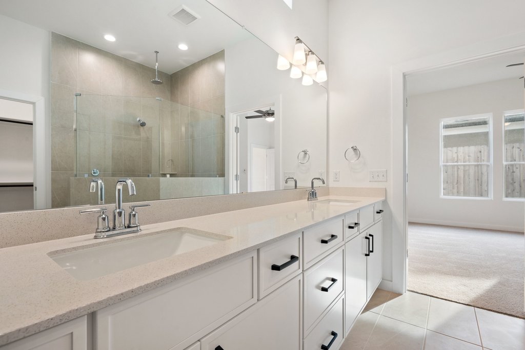 2205 Cento Walk Round Rock, TX 78664 - Photo 14 of 35 Full bathroom featuring light carpet, a shower stall, double vanity, light tile patterned floors, and ceiling fan