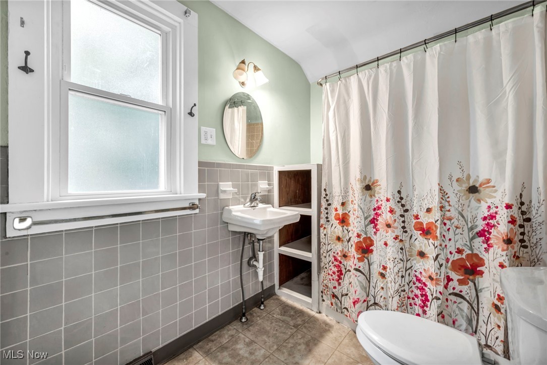 816 Perry Street Sandusky, OH 44870 - Photo 21 of 38 Full bathroom featuring tile patterned flooring, tile walls, curtained shower, and wainscoting