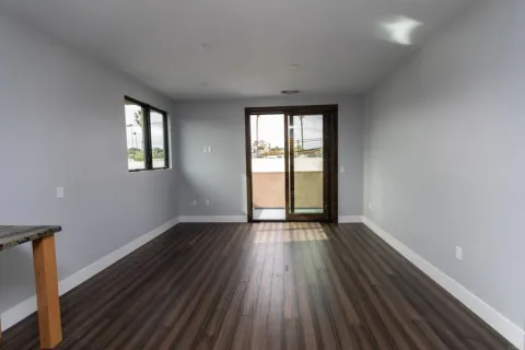 an empty room with wooden floor and windows