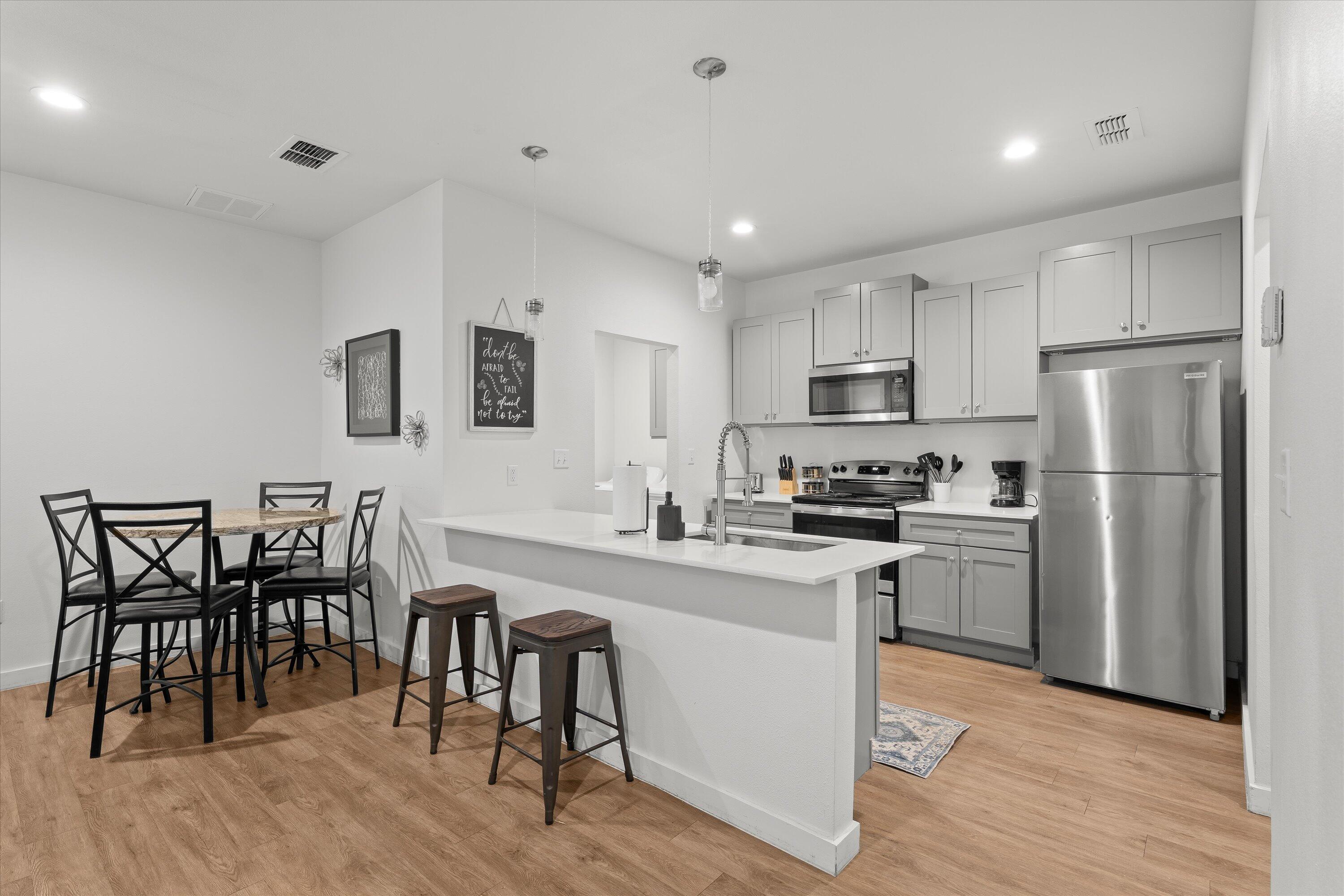 5736 Lehigh Street Lubbock, TX 79416 - Photo 6 of 23 a kitchen with cabinets wooden floor dining table and stainless steel appliances