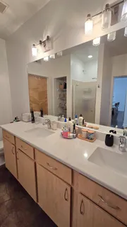 a bathroom with double vanity sinks a vanity a lamp and a mirror