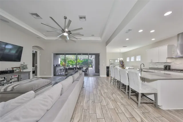 a kitchen with stainless steel appliances granite countertop a refrigerator a sink dishwasher a stove and white cabinets with wooden floor