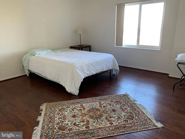 a bedroom with a bed rug and wooden floor