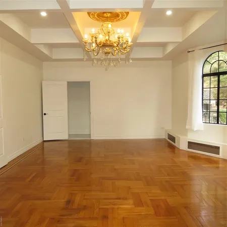 wooden floor in an empty room with a chandelier