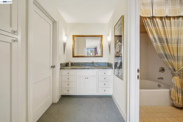 a bathroom with a granite countertop sink a mirror and a bathtub
