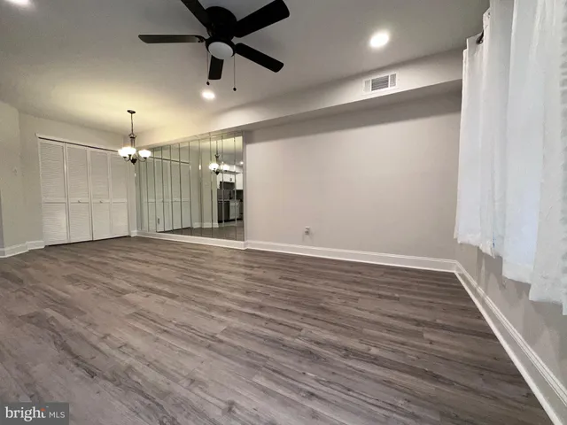 an empty room with wooden floor ceiling fan and windows