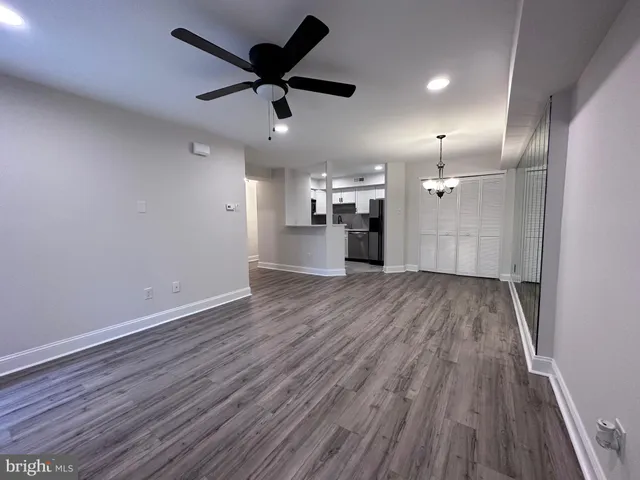 an empty room with wooden floor and a ceiling fan