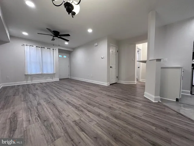 an empty room with wooden floor ceiling fan and windows