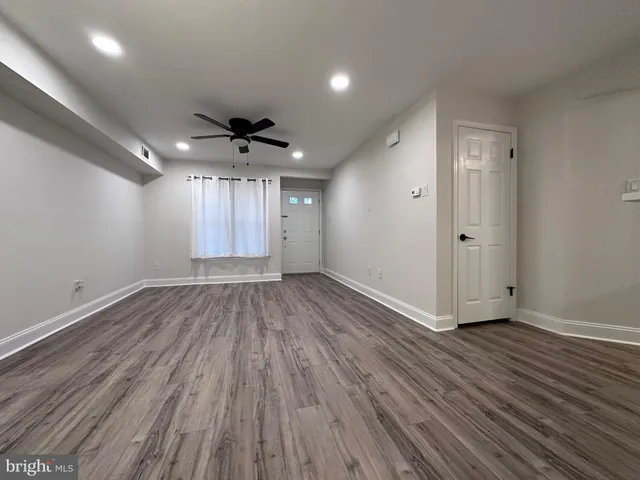 an empty room with wooden floor a ceiling fan and windows