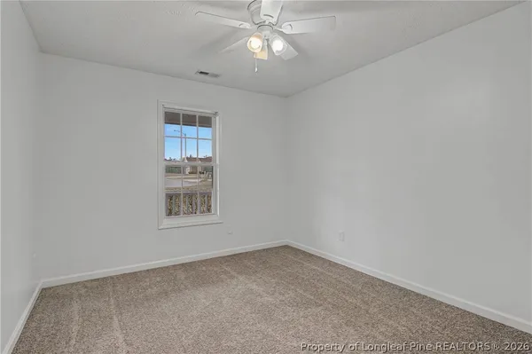 an empty room with a chandelier fan and windows