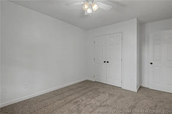 a view of an empty room with a chandelier fan