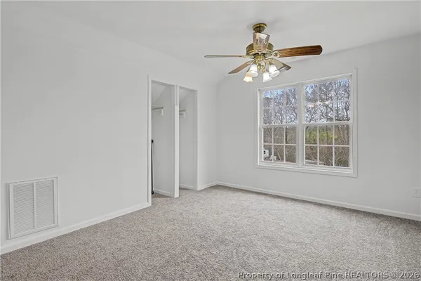 an empty room with windows and chandelier fan
