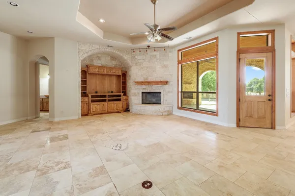 an empty room with fireplace cabinet and windows