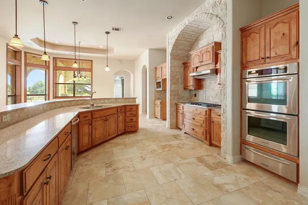 a large kitchen with stainless steel appliances granite countertop a stove and a sink