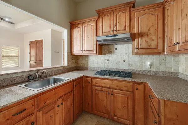 a kitchen with granite countertop a sink stove top oven and cabinets