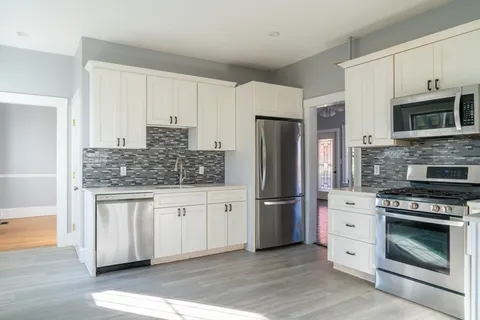 a kitchen with stainless steel appliances white cabinets a stove a sink and a refrigerator