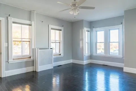 a view of an empty room with a window and wooden floor