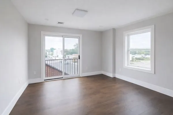 an empty room with wooden floor and windows