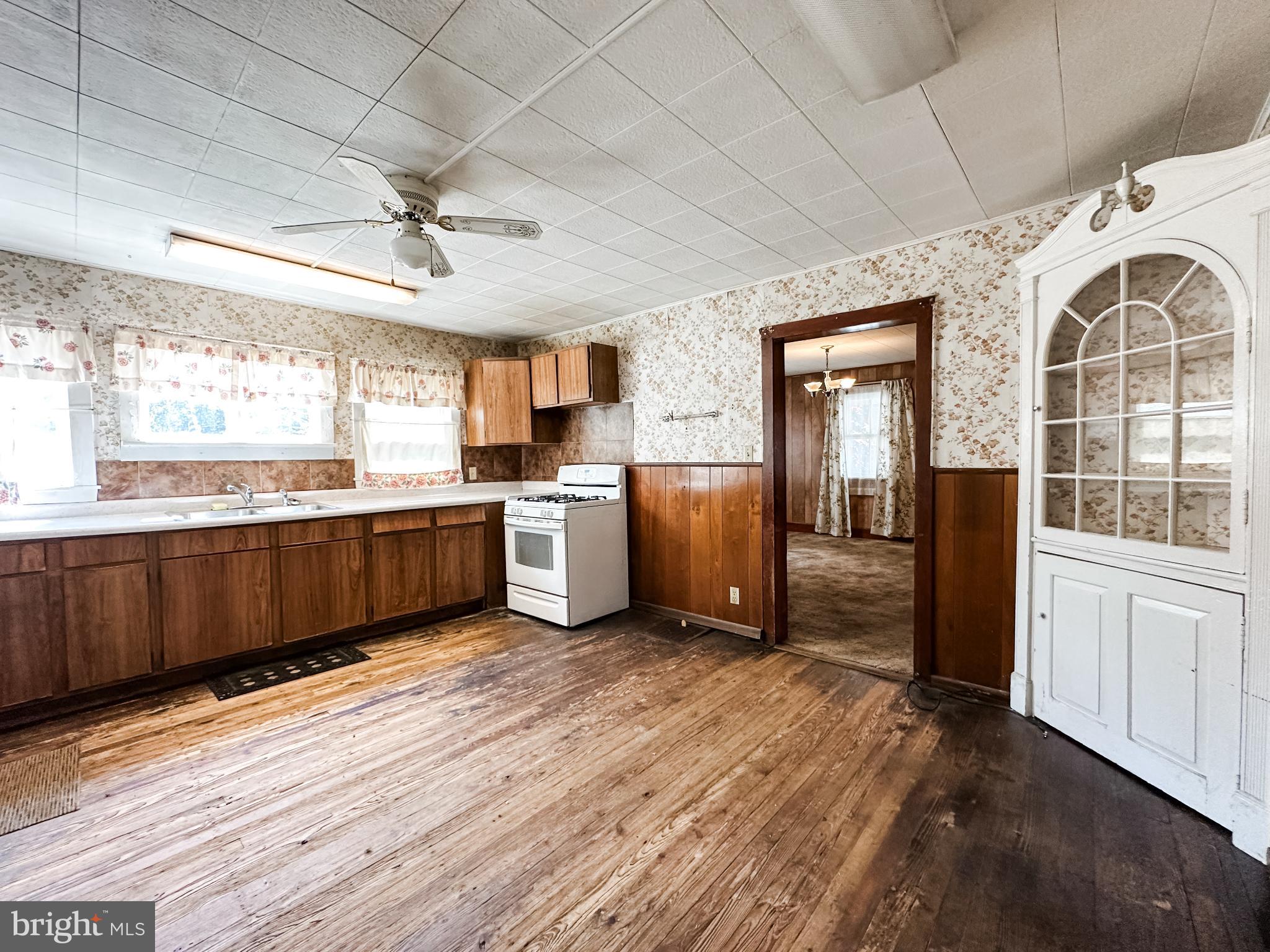 13204 Barrelville Road Northwest Mount Savage, MD 21545 - Photo 12 of 35 a kitchen with stainless steel appliances kitchen island granite countertop a refrigerator a sink dishwasher a stove and white cabinets with wooden floor