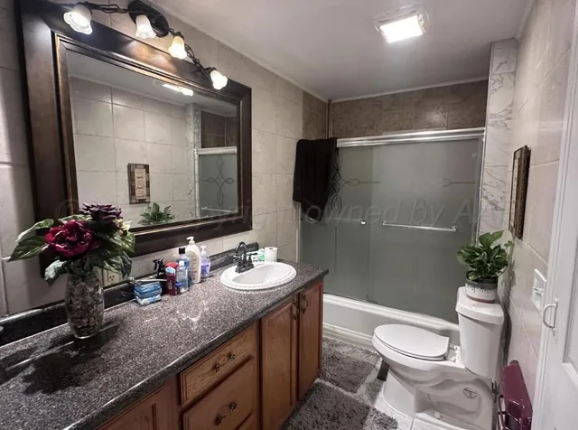 a bathroom with a granite countertop sink toilet a large mirror and shower