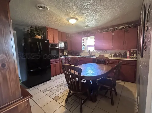 a kitchen with a table chairs a sink dishwasher refrigerator and cabinets