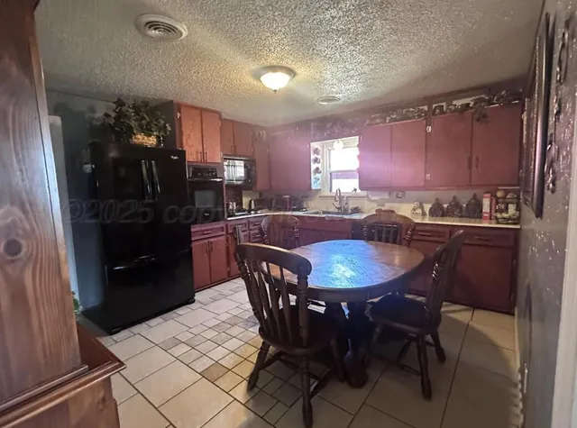 a kitchen with a table chairs a sink dishwasher refrigerator and cabinets