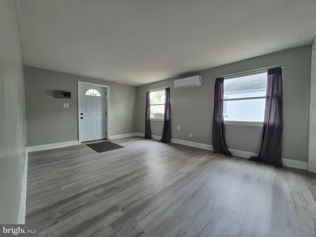 a view of an empty room with window and wooden floor