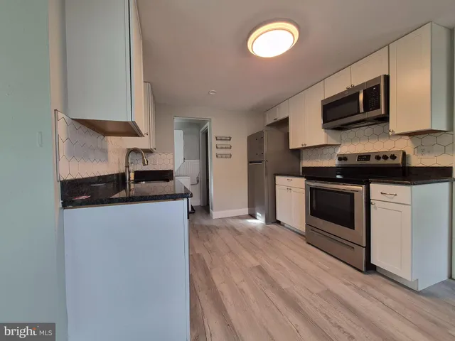 a kitchen with stainless steel appliances a stove microwave and sink