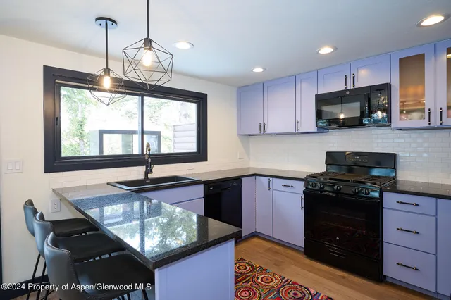 a kitchen with kitchen island granite countertop stove top oven microwave and cabinets