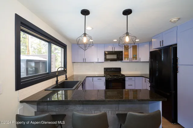 a kitchen with stainless steel appliances granite countertop a sink a stove and a refrigerator