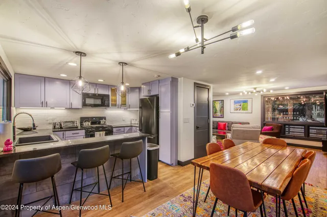 a kitchen with stainless steel appliances kitchen island granite countertop a dining table chairs and refrigerator