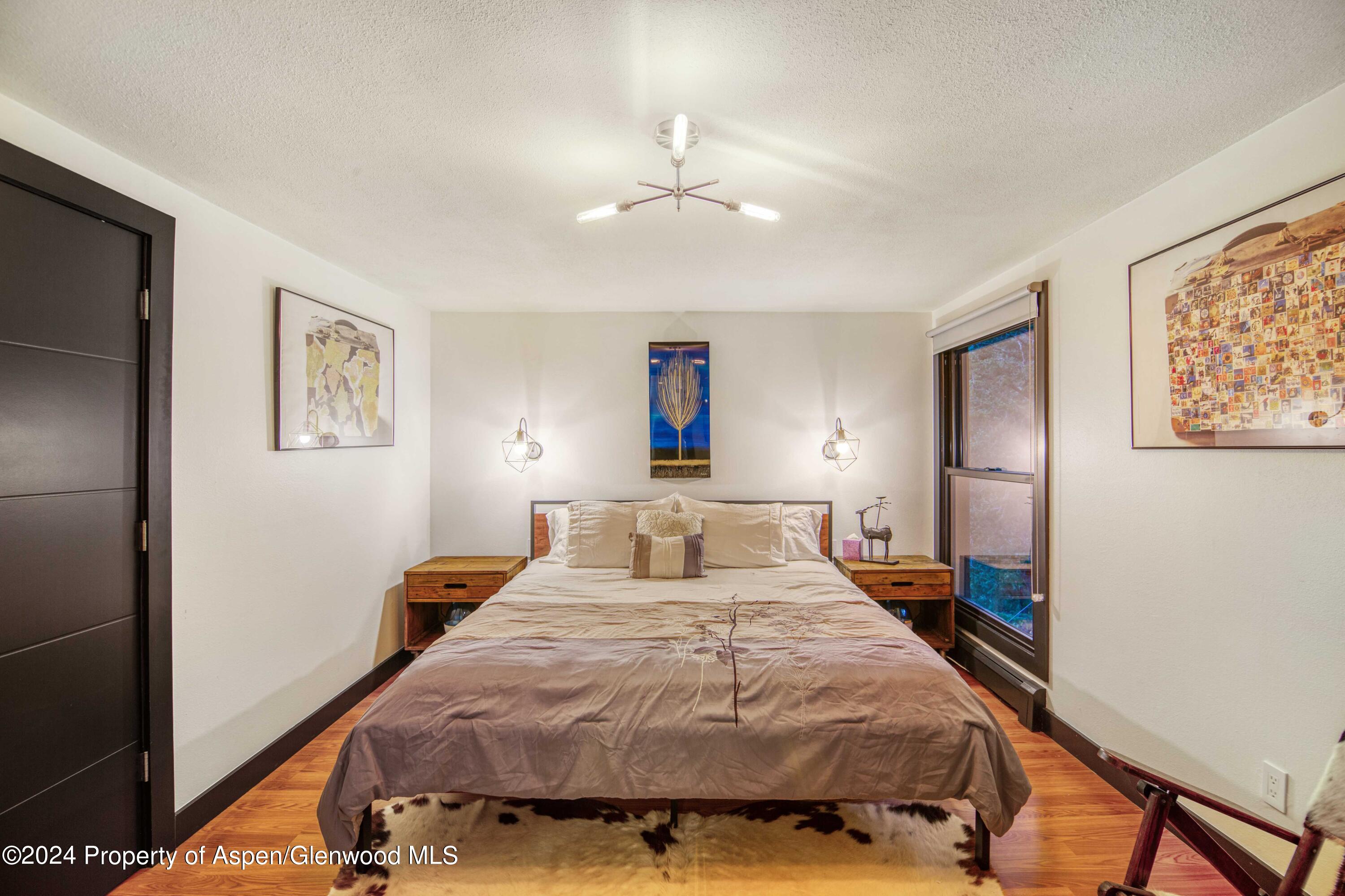 1501 Maroon Creek Road, Unit 6 Aspen, CO 81611 - Photo 39 of 48 a bedroom with a large bed and a chandelier