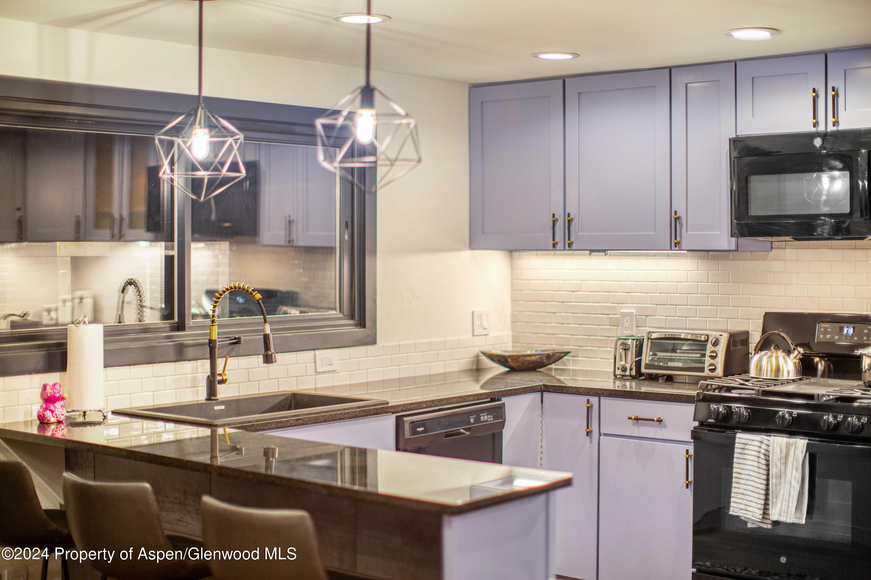 1501 Maroon Creek Road, Unit 6 Aspen, CO 81611 - Photo 47 of 48 a kitchen with kitchen island granite countertop a sink stainless steel appliances and cabinets