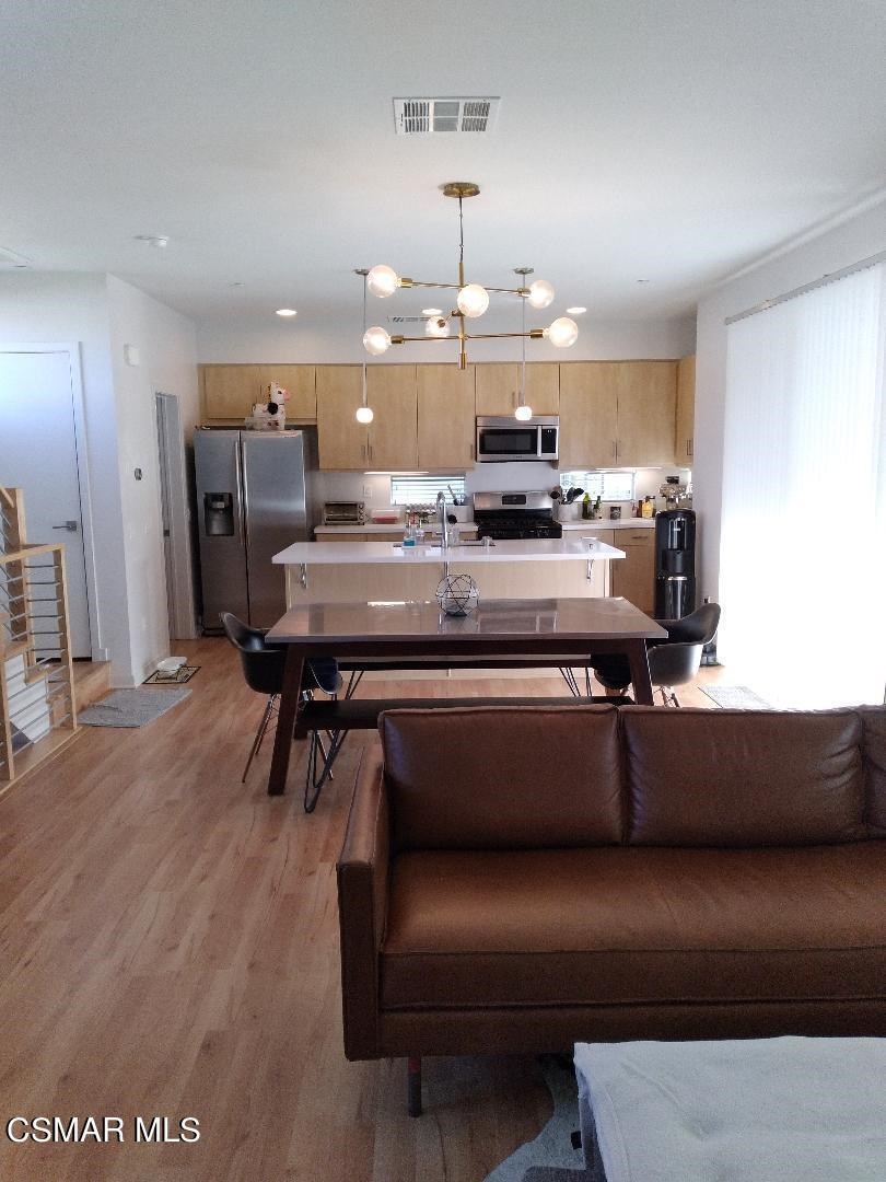 a room with kitchen island stainless steel appliances wooden floor dining table and chairs