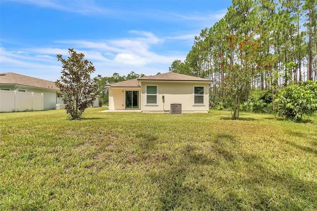 a living room with lots of furniture kitchen view and large windows
