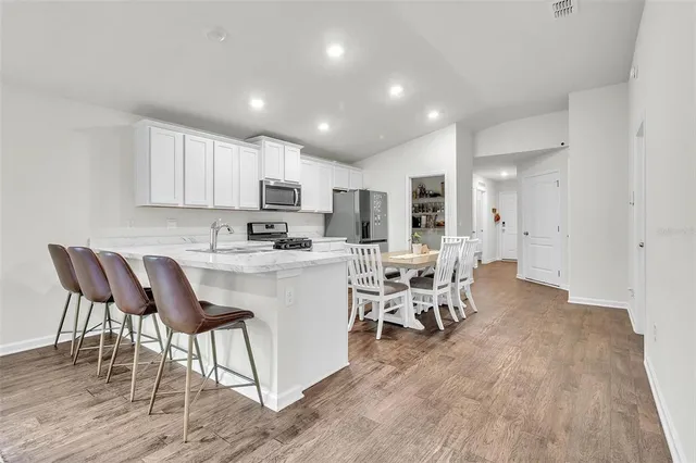 a kitchen with stainless steel appliances granite countertop a table chairs sink and cabinets