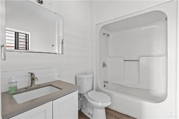 a kitchen with stainless steel appliances granite countertop a refrigerator oven a sink dishwasher and white cabinets with wooden floor