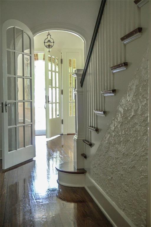 Foyer featuring french doors, dark wood-type flooring, stairway, and arched walkways