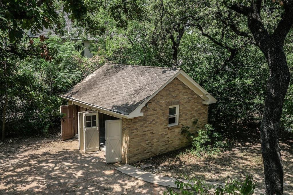 2301 Enfield Road Austin, TX 78703 - Photo 23 of 27 View of side of home featuring brick siding, a shingled roof, and a forest view