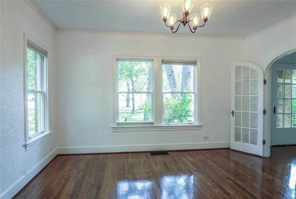 2301 Enfield Road Austin, TX 78703 - Photo 4 of 27 Empty room featuring plenty of natural light, crown molding, dark wood-style flooring, a chandelier, and arched walkways