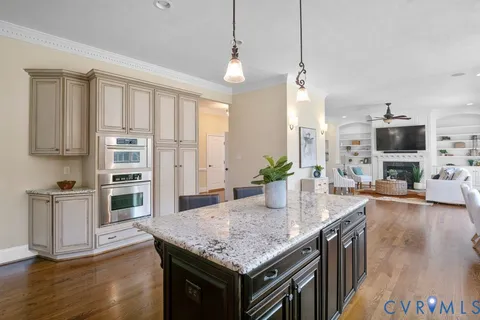 a kitchen with stainless steel appliances granite countertop a refrigerator oven stove and white cabinets with wooden floor