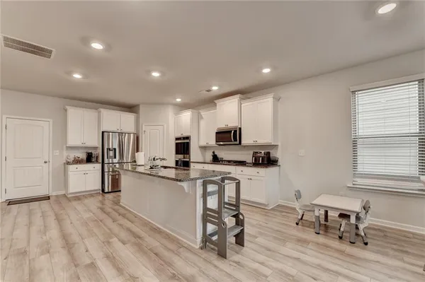 a kitchen with stainless steel appliances kitchen island granite countertop a refrigerator and wooden cabinets