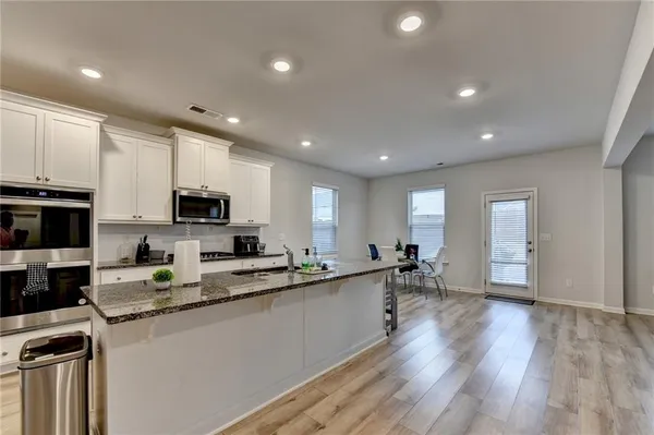 a kitchen with stainless steel appliances a sink a stove a microwave a center island and a refrigerator