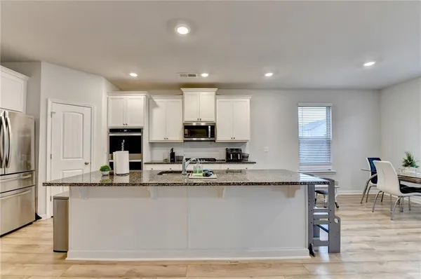 a large kitchen with granite countertop a large counter top stainless steel appliances and cabinets
