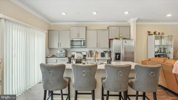 a kitchen with stainless steel appliances granite countertop a dining table chairs refrigerator and cabinets