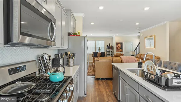 a kitchen with stainless steel appliances granite countertop a sink a stove and a wooden floors