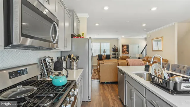 a kitchen with stainless steel appliances granite countertop a sink a stove and a wooden floors