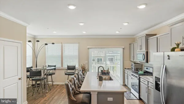 a kitchen with stainless steel appliances a refrigerator a table and chairs