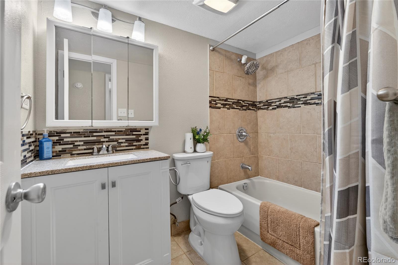 4400 South Quebec Street, Unit 101P Denver, CO 80237 - Photo 17 of 26 a bathroom with a granite countertop sink mirror vanity and toilet